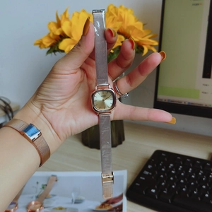 Elegant rose gold square dial watch with mesh strap for women on a stylish desk background