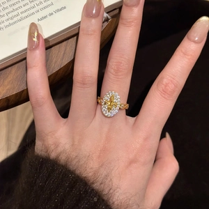 18k gold plated oval ring with zircon pavé and fleur-de-lis emblem worn by a model