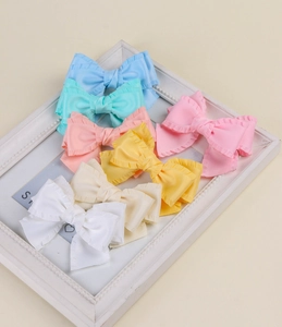 Détail de barrettes à nœuds en tissu à volants disposées dans un cadre blanc vintage