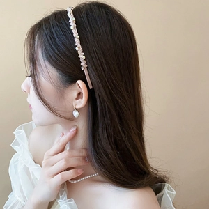 Gros plan d'un serre-tête en cristal rose et de boucles d'oreilles en perles