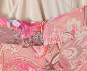 Detail of invisible pink zipper on paisley pattern resort dress with smooth cream fabric