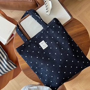 Gros plan d'un sac cabas en denim bleu à pois blancs avec un écusson sur une table