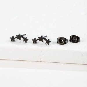 Détail des boucles d'oreilles étoiles en acier inoxydable noir sur socle en pierre