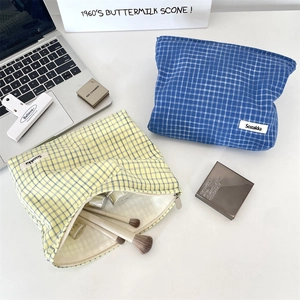 Detail of blue and yellow plaid makeup bags with zipper closure and brand woven label