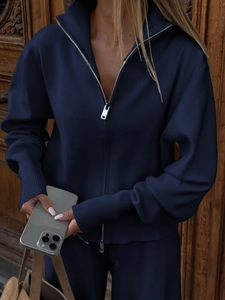 Detail of navy blue knitted sweater jacket featuring silver zipper and ribbed cuffs for women