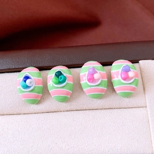 Detail of oval striped earrings with colorful beads and polished resin finish