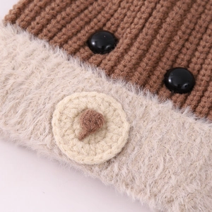 Dettaglio ravvicinato del cappello da orso marrone con bordo in peluche e occhi a bottone