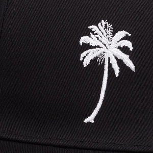 Macro view of high-density white palm tree embroidery on black mesh trucker cap fabric