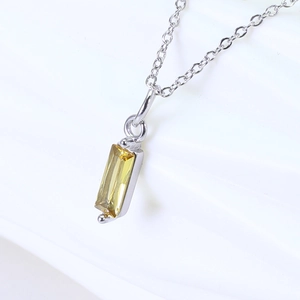 Macro shot of a rectangular yellow zircon stone pendant on a silver link chain necklace