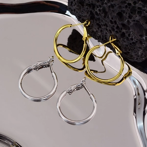 Minimalist large hoop earrings in gold and silver finish on artistic silver tray