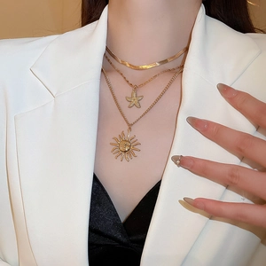 Detail view of gold layered necklaces with starfish and sun pendants on white blazer