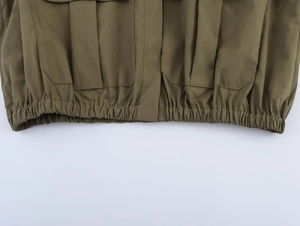 Detail of army green utility jacket featuring cargo pockets and elasticated hemline