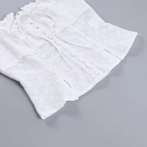Détails de broderie en dentelle blanche avec lacets croisés et boutons sur le haut