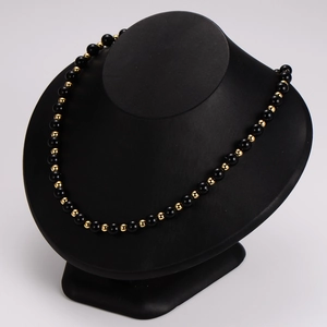 Polished black and gold beaded necklace displayed on a professional black mannequin stand