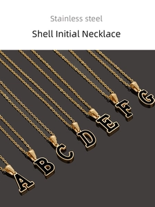 Primer plano de collares con iniciales A-G de acero inoxidable en fondo oscuro reflectante