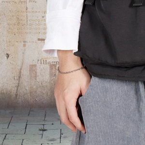 Close-up of minimalist silver stainless steel O-link chain bracelet on male wrist