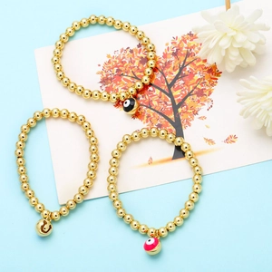Vista macro dettagliata di bracciali con perline placcati oro 18K e ciondoli evil eye