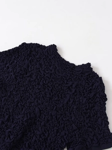 Detail view of dark blue textured knit top with bubble crepe fabric and round neckline