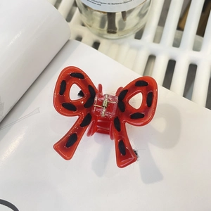 Détail de la pince à cheveux noeud rouge à pois noirs et ressort métallique