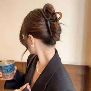 Detail view of large tortoiseshell acetate hair claw clip styled on a woman's bun