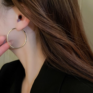 Close-up of model wearing large gold hoop earrings with a polished metallic finish