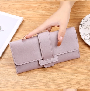 Detail of light purple wallet with pebbled leather texture and wide strap buckle closure