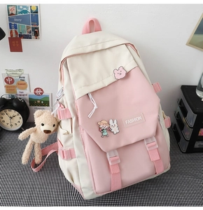 Detail des rosa-beigen Nylon-Rucksacks mit modischen Patches und niedlichen Cartoon-Ansteckern
