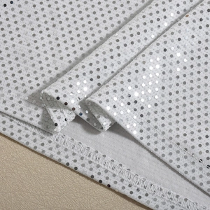 Gros plan détaillé de paillettes argentées cousues sur une texture de tissu en maille