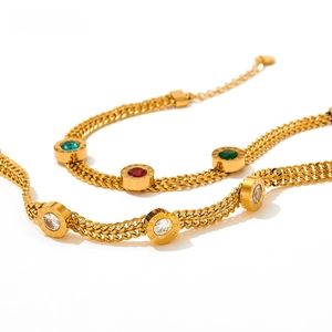 Detail of gold snake chain bracelet featuring Roman numerals and colorful gemstones