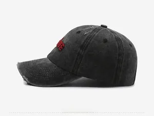 Side view of distressed washed denim baseball cap with vintage embroidery and torn holes