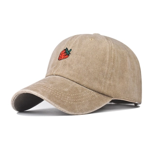 Detail of strawberry embroidery on a washed khaki cotton baseball cap with curved brim