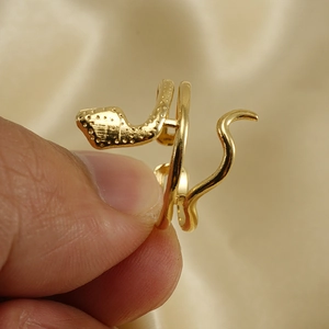 Detailed view of adjustable golden snake ring with textured scales on champagne silk
