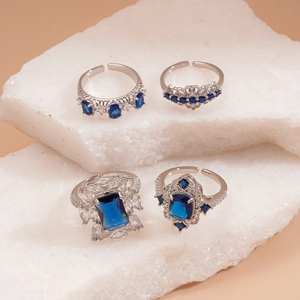 Retro geometric open rings set with blue zircon stones on textured stone display