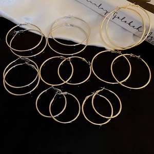 Detailed close-up of various sized minimalist silver hoop earrings on a black surface