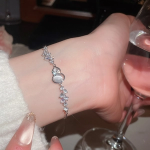 Detailed view of silver flower bracelet with cat eye stone worn on a female wrist