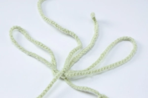 Detailed macro view of light green woven braided drawstrings on a soft fabric dress