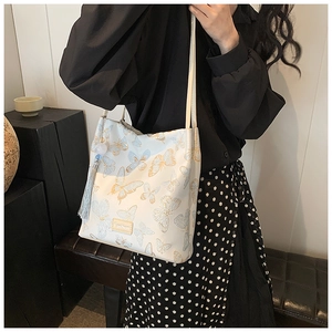 Detail of white shoulder bag with blue butterfly embroidery and elegant tassel charm