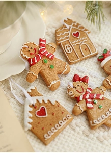 Macro shot of gingerbread man and house resin ornaments on a white knitted fabric