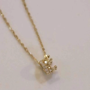 Macro shot of gold-plated crown pendant necklace with sparkling cubic zirconia inlay