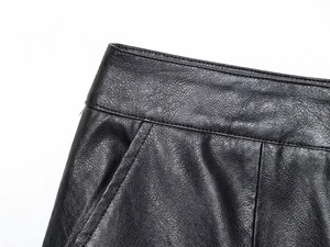 Detail of premium black faux leather shorts showing precise stitching on waist and pockets