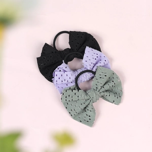 Detailed shot of three eyelet fabric bow hair ties in black, lavender and dusty green