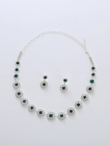Detail of silver bridal jewelry set with emerald green round gems and crystal halo