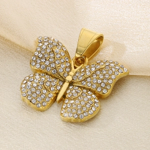 Macro shot of a gold butterfly pendant with crystals on beige silk fabric background