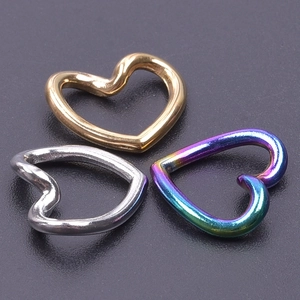 Macro shot of three stainless steel heart-shaped pendants in gold, silver and rainbow finish