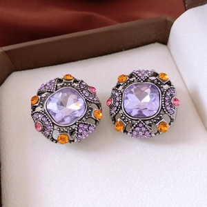 Close-up of vintage square purple crystal earrings with orange diamond accents in a box