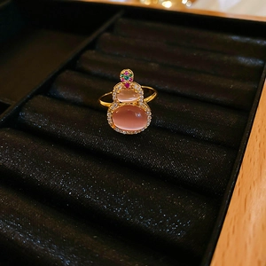 Macro view of pink cat eye stone gourd earring with zircon accents on black velvet