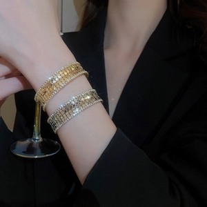 Detailed view of layered gold bangle featuring fish scale texture and cubic zirconia edges