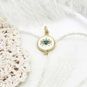 Dettaglio macro del ciondolo occhio del male dorato con gemma blu e cristalli micro-pave