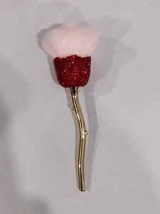 Macro view of rose flower makeup brush with red crystal bud and pink bristles