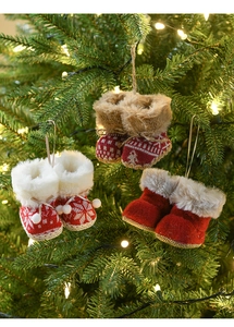 Close-up of mini knitted Christmas boots hanging on a tree with warm fairy lights